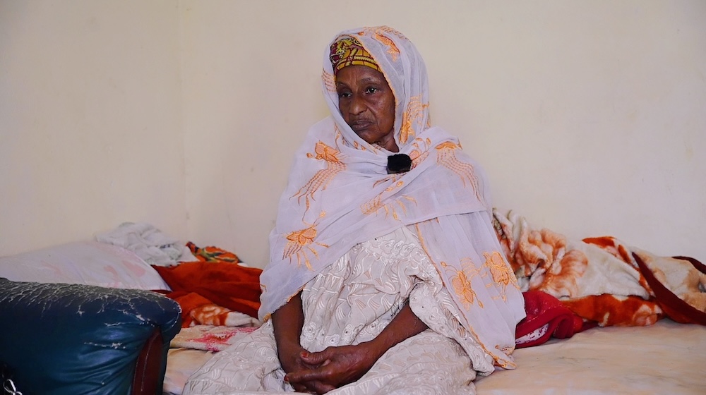 A woman sits on a bed.