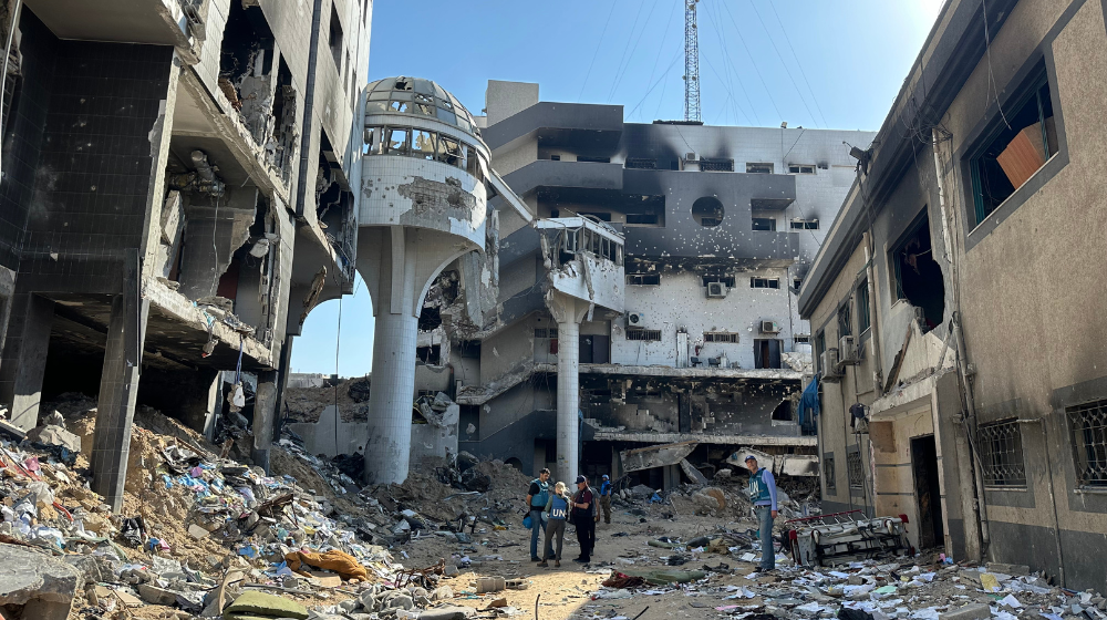  Four people in UN vests stand amid the rubble of a destroyed building