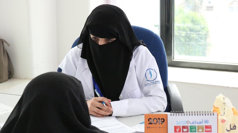  A psychosocial counsellor speaks to a woman at a desk.