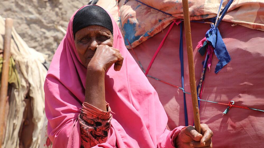 A woman sits by her home.