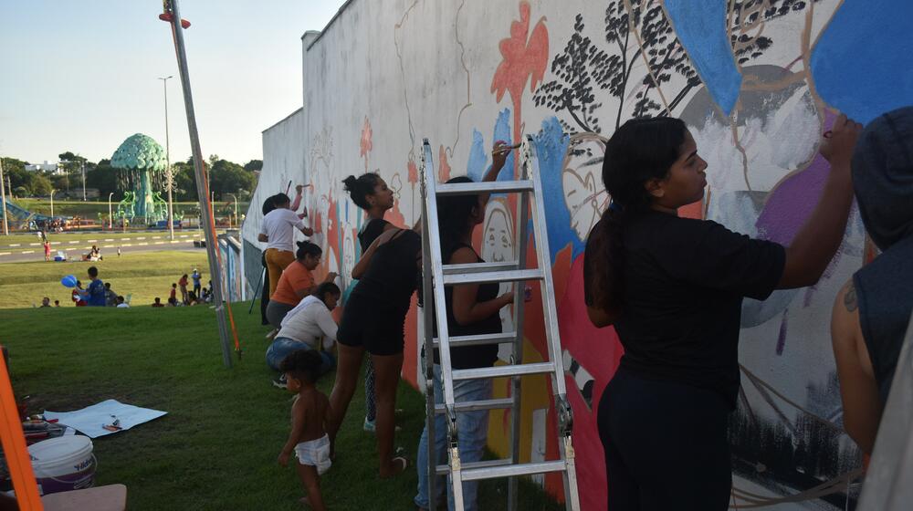 A group of women and girls paint in a park.