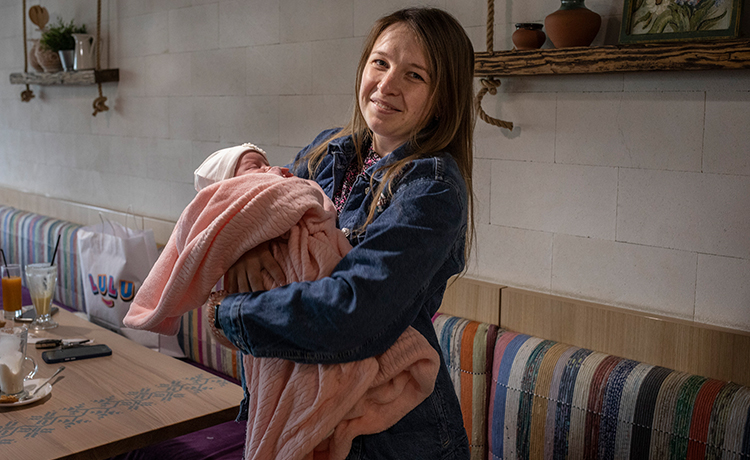 a mother, smiling, holds her infant child in her hands.