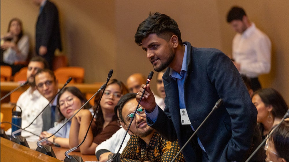 man speaking into microphone next to audience