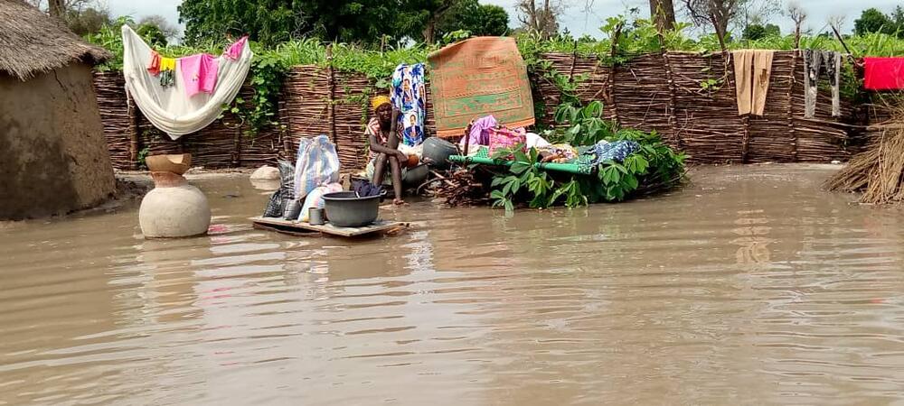 Une femme est assise au milieu de ses affaires, entourée par les eaux