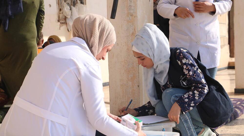 Two women sort medical supplies.