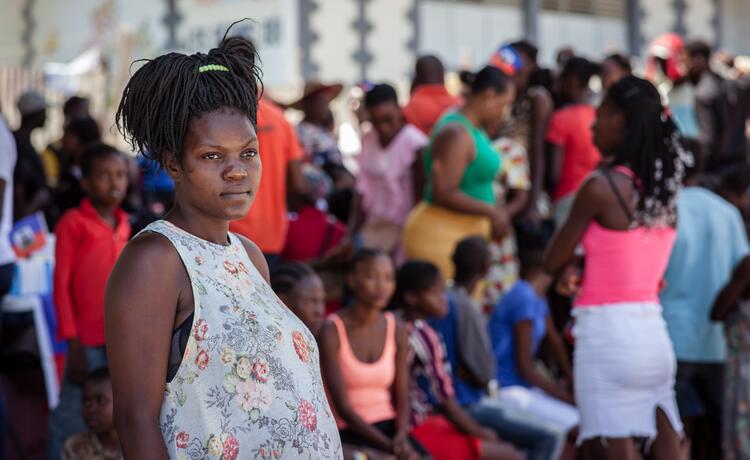 A pregnant woman stands in front of a crowd of people