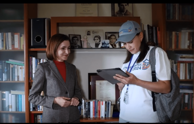 A woman holding a tablet interviews another woman.]