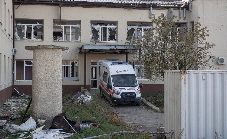 An ambulance in front of a damaged building.