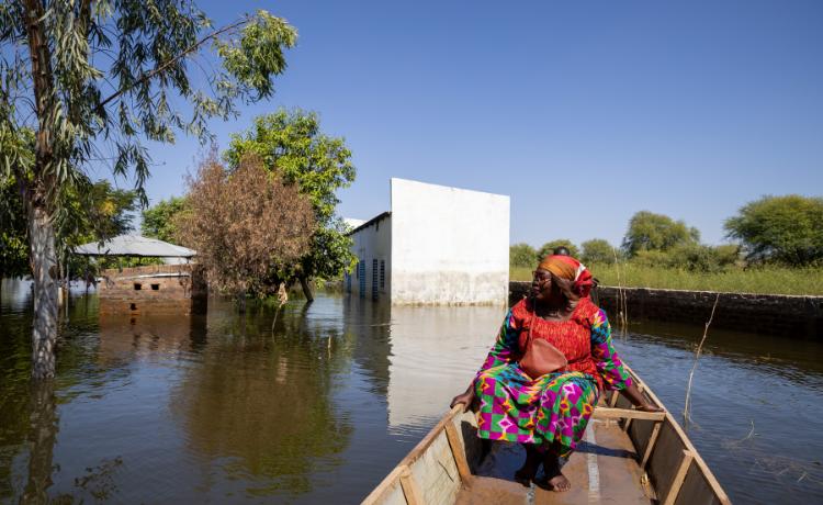 Woman in red dress sits in a boat on water