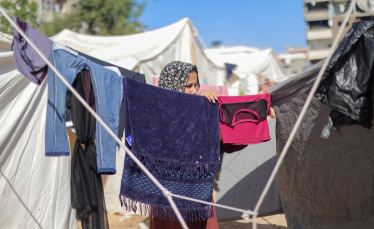 A girl hangs up laundry strung between tents