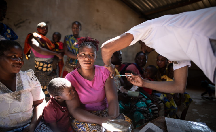 A  woman wearing pink smiles slightly as she prepares to receive a contraceptive shot.