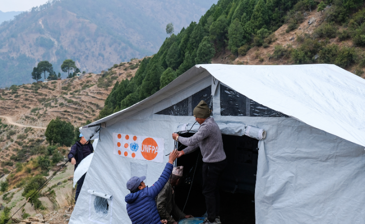  A man in a UNFPA sweatshirt helps to set up a tent that will serve as a mobile clinic