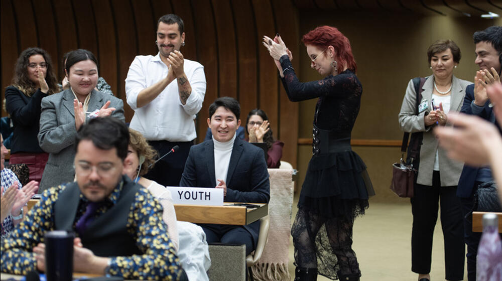 A small group of people claps for a young speaker.