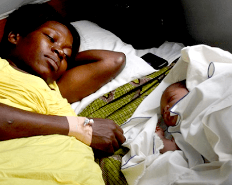 A woman lies next to her infant.