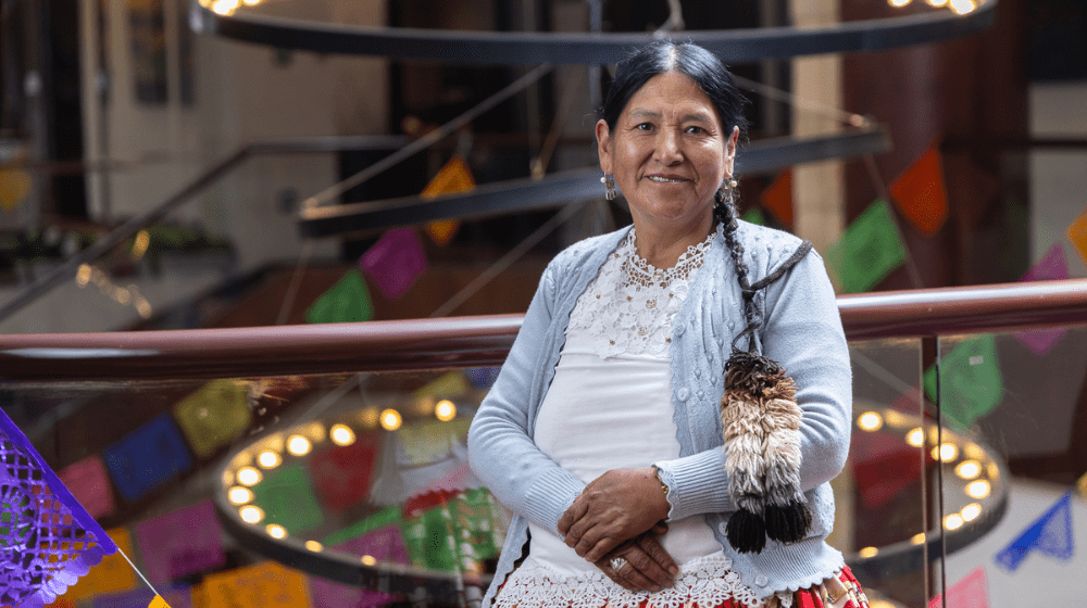  A woman wearing traditional clothes and a long braid smiles at the camera.