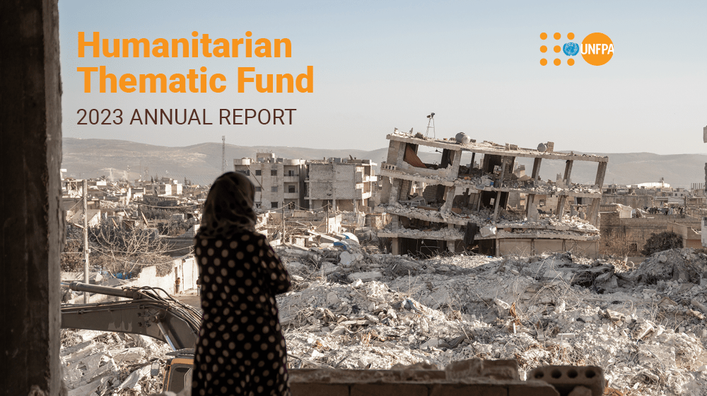 A woman in a beige hijab  and polka dot dress stands in a desolate building and looks out at the concrete destruction from an earthquake