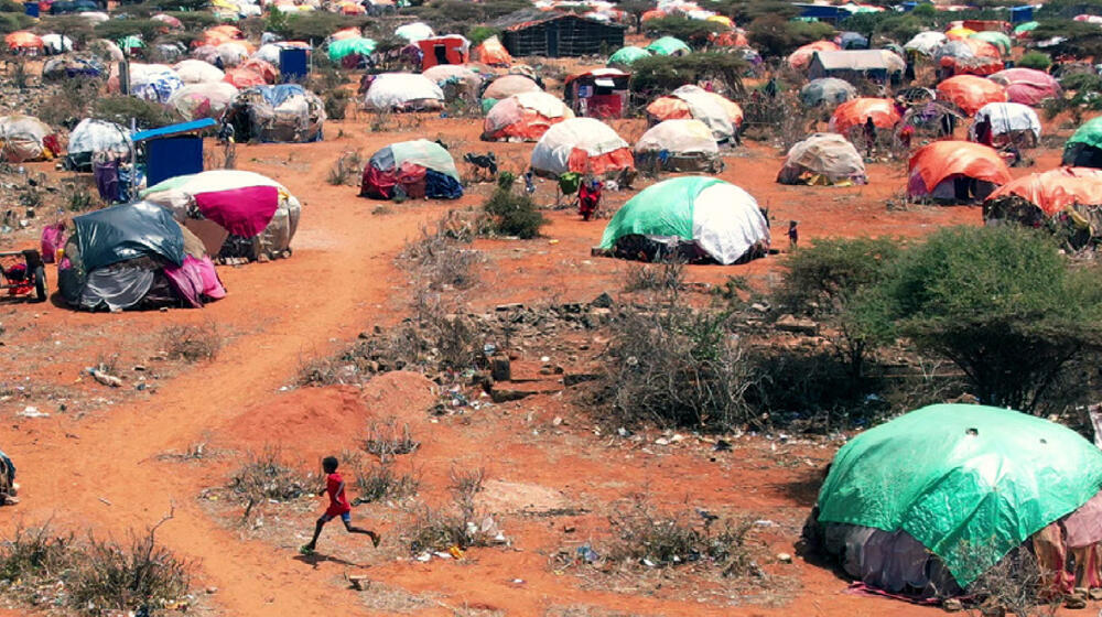 A young boy runs through a camp.