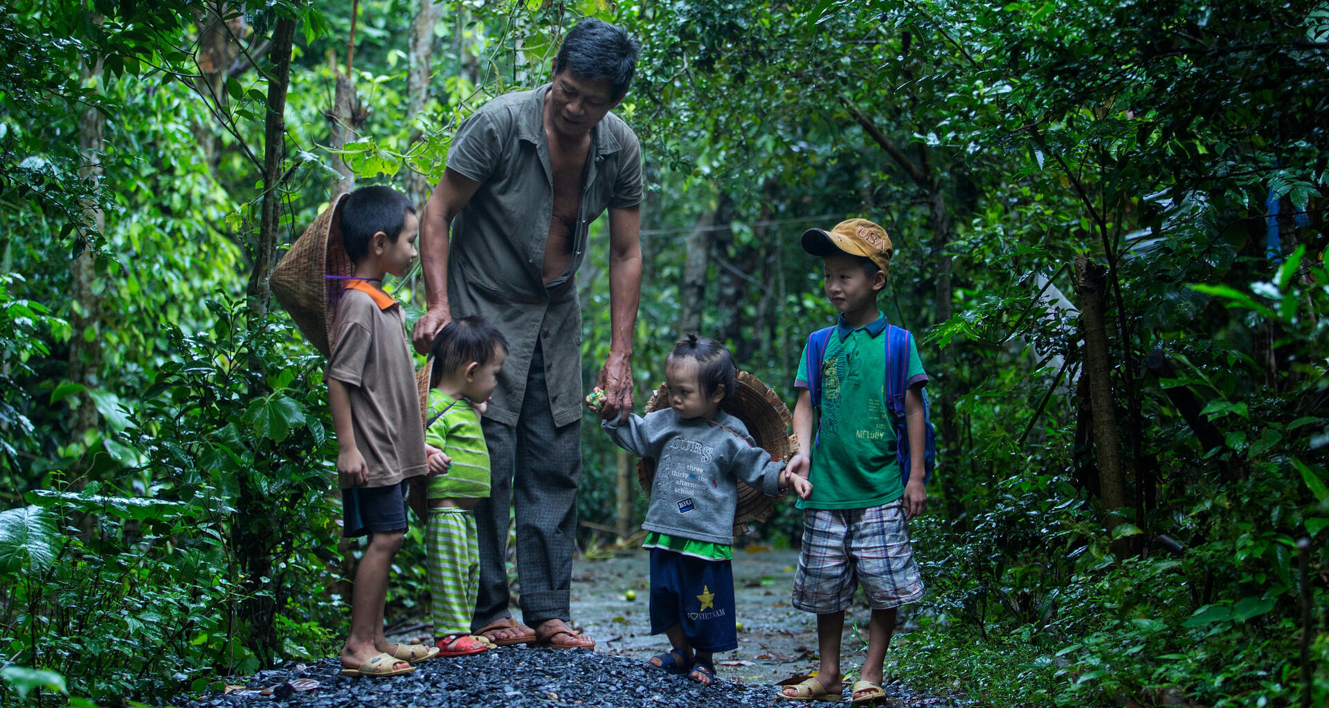 Un homme se tient avec de jeunes enfants.