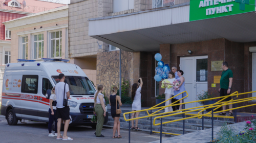 People greet a new mother outside a hospital.